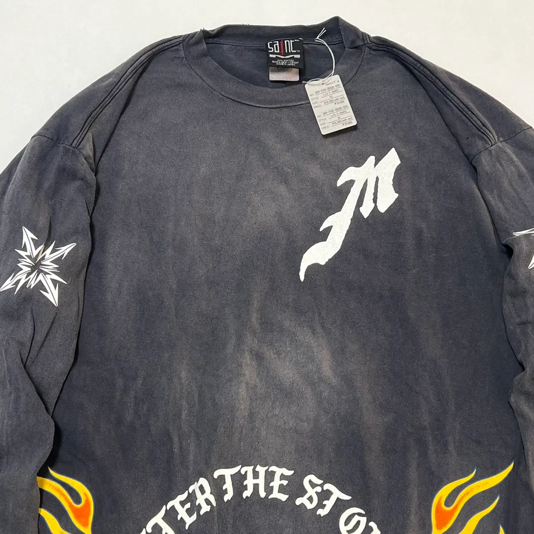 SAINT Mxxxxxx M/AFTER LS_TEE/BLACK Flame arrow Letter M retro distressed long tee Washed black S-XL Tubular fabric Assute ready-made garments dyed The whole piece is sprayed with horse-hair spray and then sprayed again to fade the color. The collar and cuffs are frayed. Many places are frayed. Extra large printing position. Very difficult to print. Complete accessories. With little angel anti-counterfeiting label.